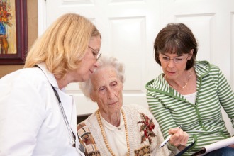 Angehörige und Ärztin betreuen Seniorin